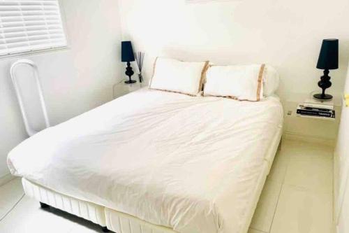 a white bed in a white bedroom with two lamps at small villa tokyo 渋谷まで2駅10分 青山一丁目駅徒歩3分一軒家ペット歓迎お子様歓迎駐車場あり6人までOK in Tokyo