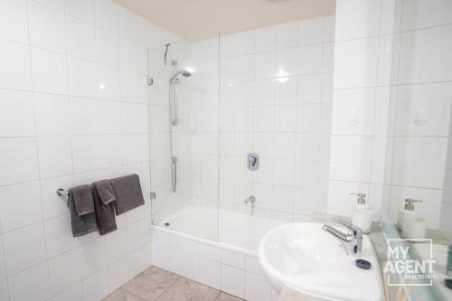 een witte badkamer met een wastafel en een bad bij Spacious Apartment in Southbank - Sleeps 6 in Melbourne