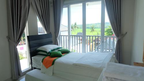 a bedroom with a bed in front of a balcony at Villa Jogja Grand Bale with Private Pool by Simply Homy in Yogyakarta
