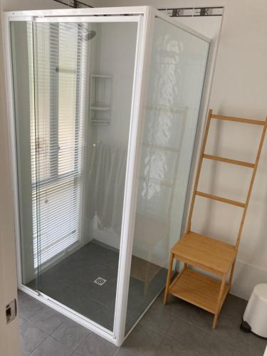 a glass shower with a wooden chair next to a mirror at Bay views on Laurie in Encounter Bay