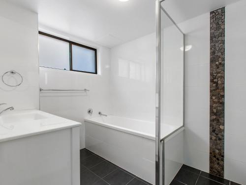a white bathroom with a sink and a shower at Creekfront Kingscliff Waters 2 in Kingscliff