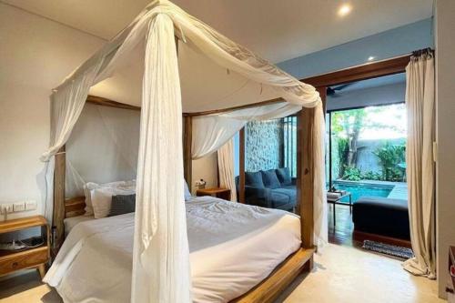 um quarto com uma cama de dossel e uma sala de estar em Zenith villa Pererenan em Munggu