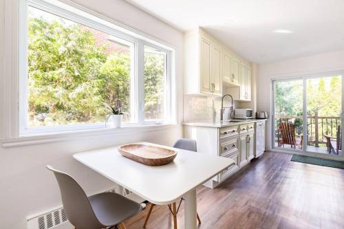 eine Küche mit einem weißen Tisch und 2 Fenstern in der Unterkunft Bright Riverfront 3-Bedroom Condo in Montreal
