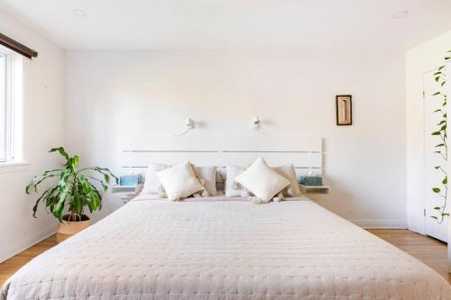 een witte slaapkamer met een groot bed met kussens bij Bright Riverfront 3-Bedroom Condo in Montreal