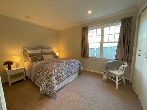 a bedroom with a bed and a chair and a window at Refined, Retro & Relaxing in Paraparaumu