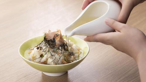a person feeding a bowl of food with a spoon at Hotel Nishinagato Resort in Takibe