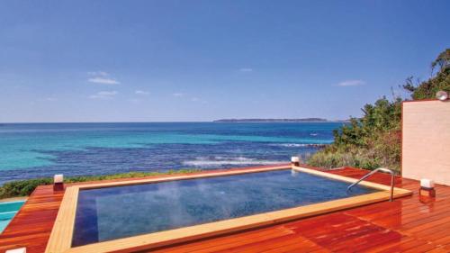 a swimming pool on the deck of a house with the ocean at Hotel Nishinagato Resort in Takibe