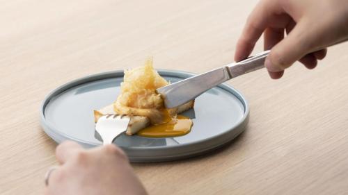 a person is eating a piece of food on a plate at Hotel Nishinagato Resort in Takibe