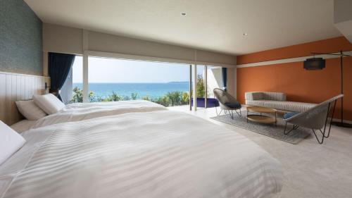 a bedroom with a large white bed and a view of the ocean at Hotel Nishinagato Resort in Takibe