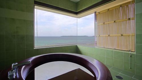 a bathroom with a sink and a window with the ocean at Hotel Nishinagato Resort in Takibe