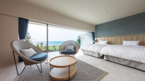 a hotel room with a bed and chairs and a large window at Hotel Nishinagato Resort in Takibe