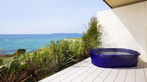 a large blue tub sitting on a balcony overlooking the ocean at Hotel Nishinagato Resort in Takibe