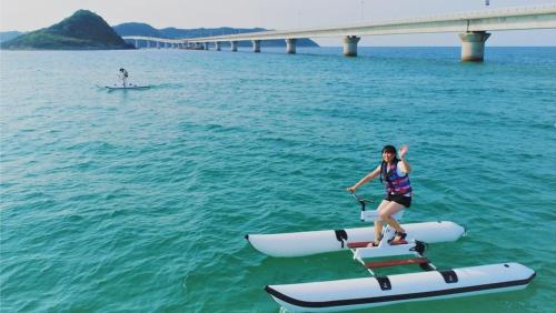 a woman is standing on a paddle board in the water at Hotel Nishinagato Resort in Takibe