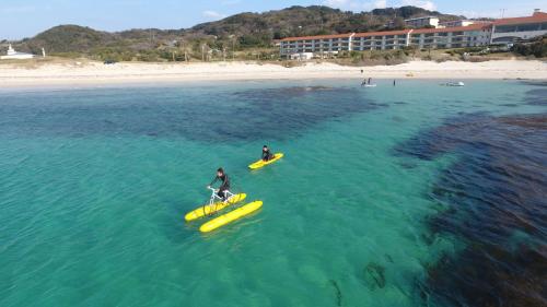 two people in the water on surfboards in the ocean at Hotel Nishinagato Resort in Takibe