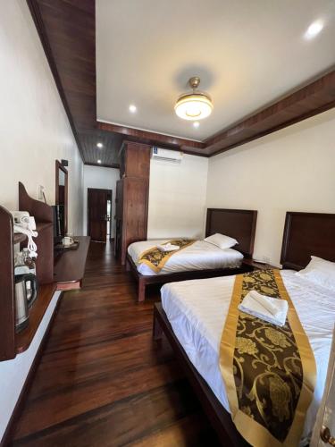 two beds in a room with wooden floors at NamKhan Riverside in Luang Prabang