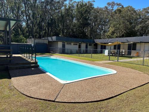 a swimming pool in a yard with a fence at Bull and Bush Hotel in Medowie