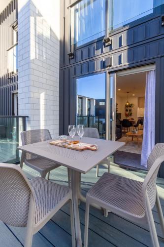 a table with wine glasses and chairs on a balcony at Central Charm 2 bed 2 bath w/ sunny Balcony in Christchurch