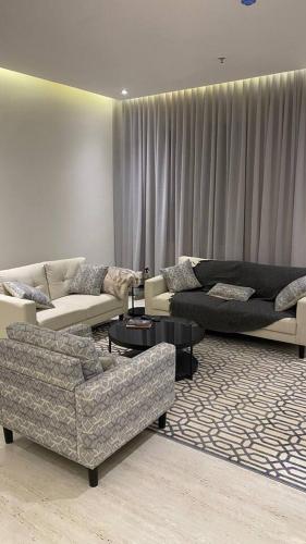 uma sala de estar com sofás, mesas e cortinas em Luxury Apartment em Riyadh