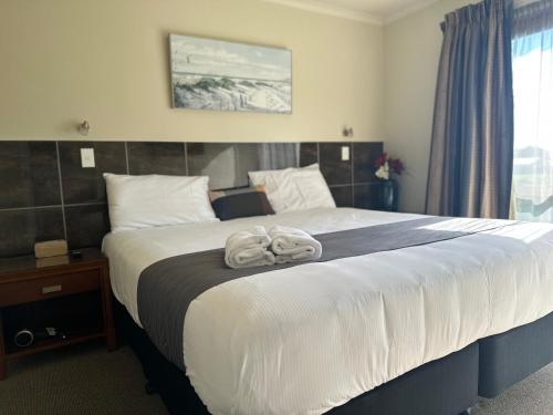 a bedroom with a large bed with towels on it at Admirals Motor Inn in Nelson