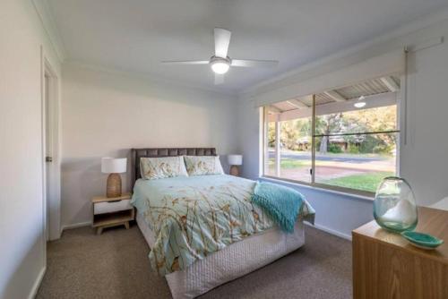 a bedroom with a bed and a large window at Lake Edge Retreat in Quindalup