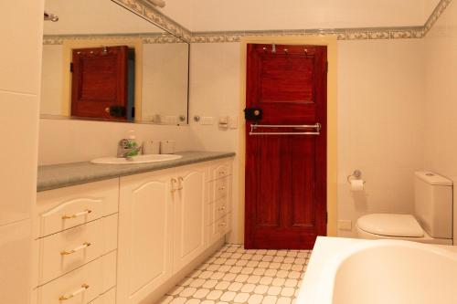 baño con lavabo y puerta roja en Redgum Cottage, en Mudgee