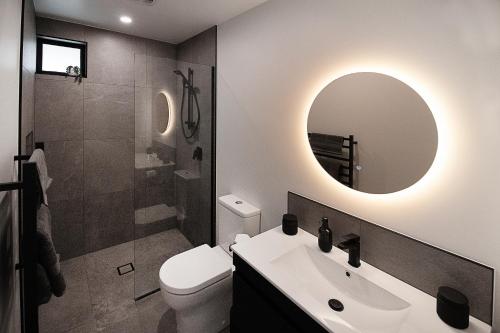 Hillbrook - a luxurious designer house في Ohauiti: حمام مع مرحاض ومغسلة ومرآة