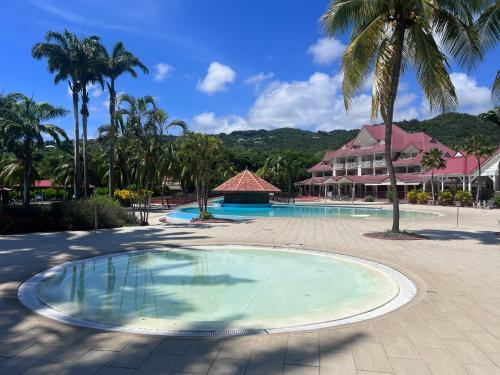 einen Pool in einem Resort mit Palmen und einem Gebäude in der Unterkunft cœur d hibiscus P&V in Sainte-Luce