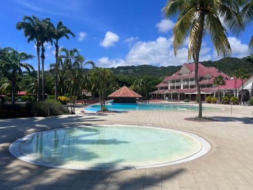 a pool at a resort with palm trees and a building at cœur d hibiscus P&V in Sainte-Luce