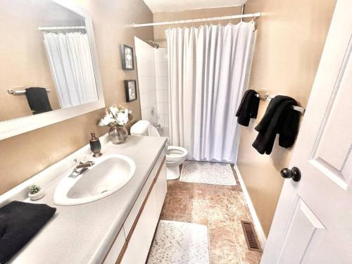 a white bathroom with a sink and a toilet at Furnished Townhouse w parking by Hospital & University! in Thunder Bay