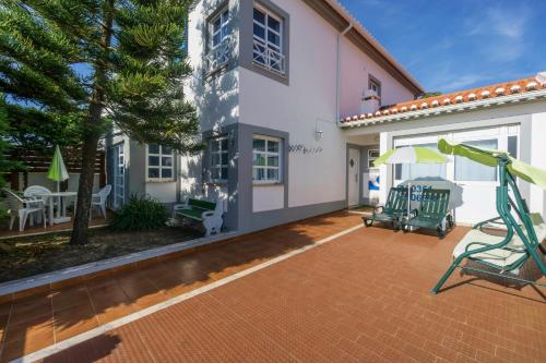 a house with a patio with a swing at H2O GuestHouse in Baleal