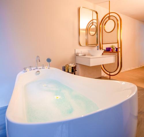 a bath tub in a bathroom with a sink at Deevana Plaza Phuket - SHA Extra Plus in Patong Beach