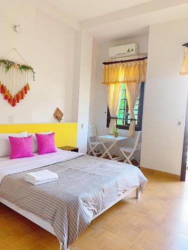 a bedroom with a bed with pink pillows and a table at Letters Bà Triệu in Liên Trì (3)