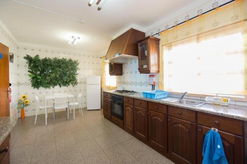 uma cozinha com armários de madeira, um lavatório e uma janela em H2O GuestHouse em Baleal