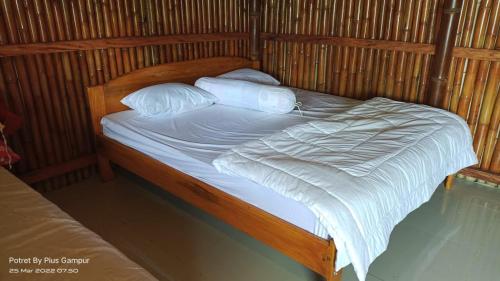 - un lit avec des draps et des oreillers blancs dans l'établissement Villa Molas, à Ruteng