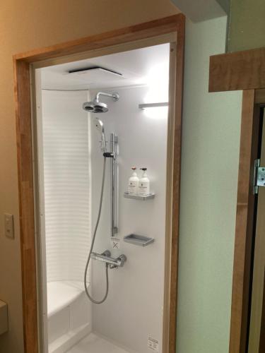 a shower in a bathroom with a sink and a tub at Komatsuya Seki Onsen in Myoko