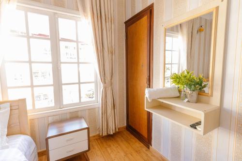 a bedroom with a mirror and a bed and a window at BACH TUNG Garden Village Đà Lạt in Xuan An
