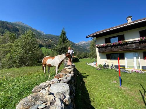 a man and a horse standing next to a rock wall at Apartment Haus Christina in Großkirchheim