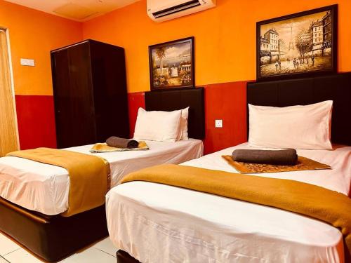 - 2 lits dans une chambre aux murs orange dans l'établissement Smart Budget Hotel - Klang, à Klang