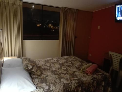 a bedroom with a bed and a large window at Posada Peregrinus in Lima