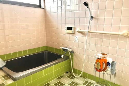 La salle de bains est pourvue d'une baignoire avec un tuyau. dans l'établissement ゲストハウスわかばGuestHouse Wakaba in Iwami, à Iwamicho