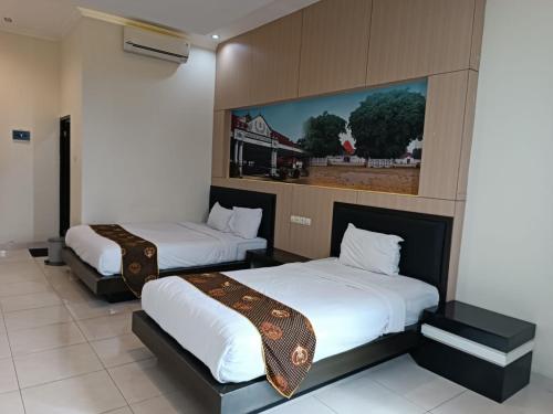 a room with two beds and a painting on the wall at Shafira Hotel Yogyakarta in Ngabean