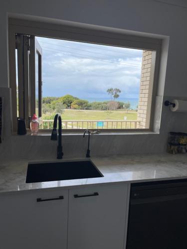 eine Küchentheke mit einem Waschbecken und einem Fenster in der Unterkunft Oceanview in Woorim