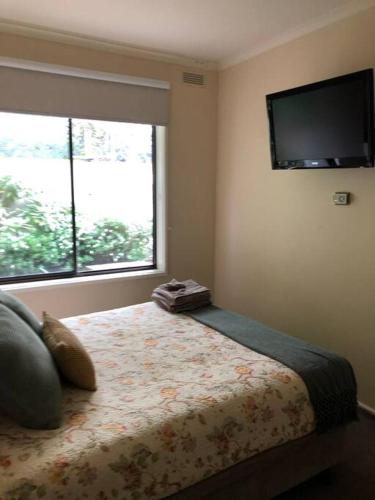 a bedroom with a bed with a television on the wall at Lake Apartment in Wendouree