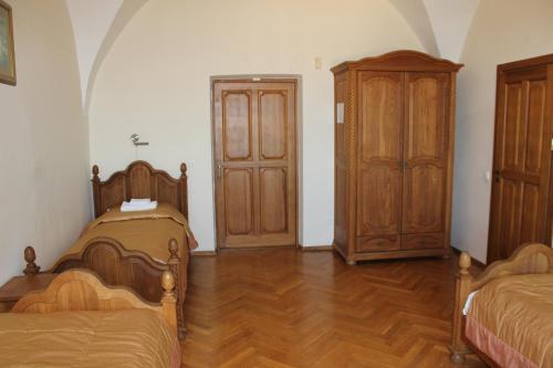 a room with two beds and a wooden cabinet at Liškiavos vienuolyno ansamblis in Liškiava