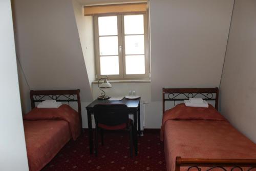 a room with two beds and a desk and a window at Liškiavos vienuolyno ansamblis in Liškiava