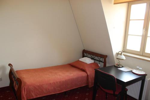 a small room with a bed and a table and a window at Liškiavos vienuolyno ansamblis in Liškiava