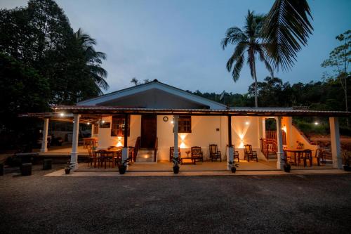 a house with a porch with chairs and tables at Glitz Marriott in Deniyaya