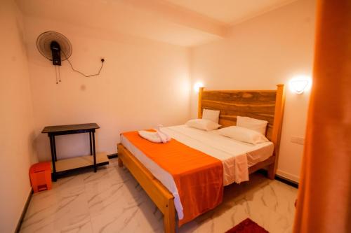 a bedroom with a bed with an orange blanket at Glitz Marriott in Deniyaya