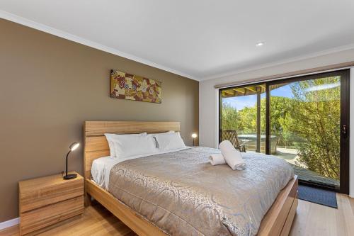 a bedroom with a bed and a large window at Achilles in Apollo Bay