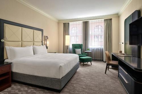 a hotel room with a bed and a green chair at JW Marriott Chicago in Chicago